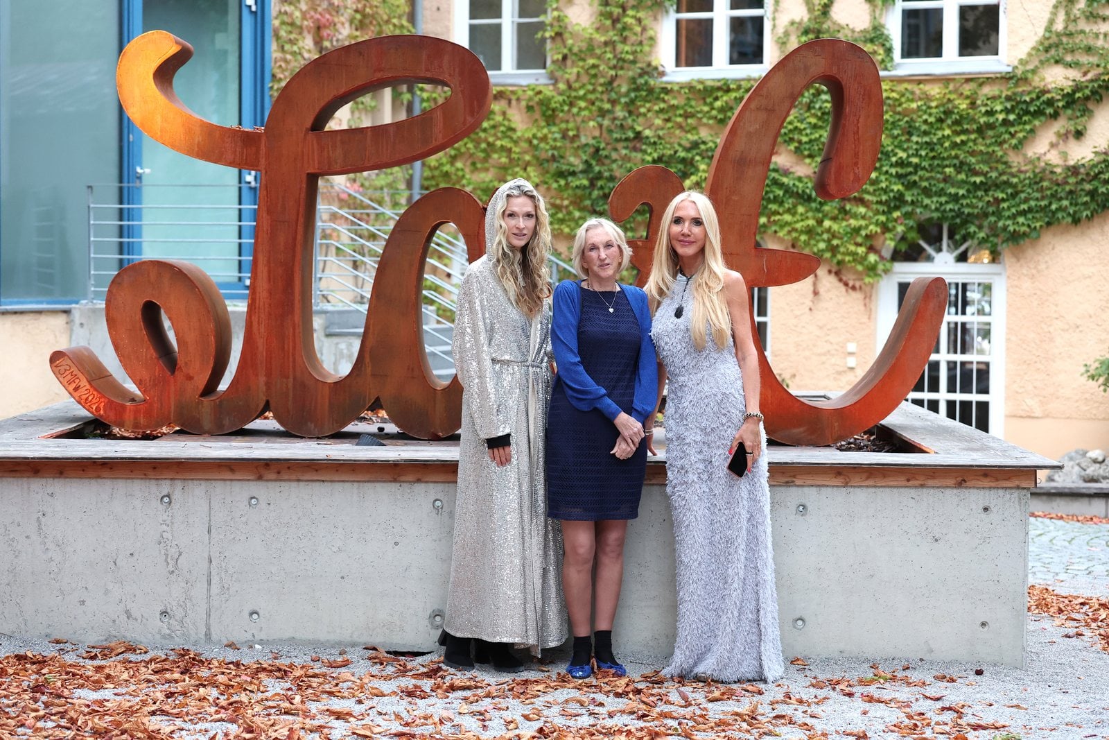 Drei Frauen stehen vor einer großen rostfarbenen Love-Skulptur