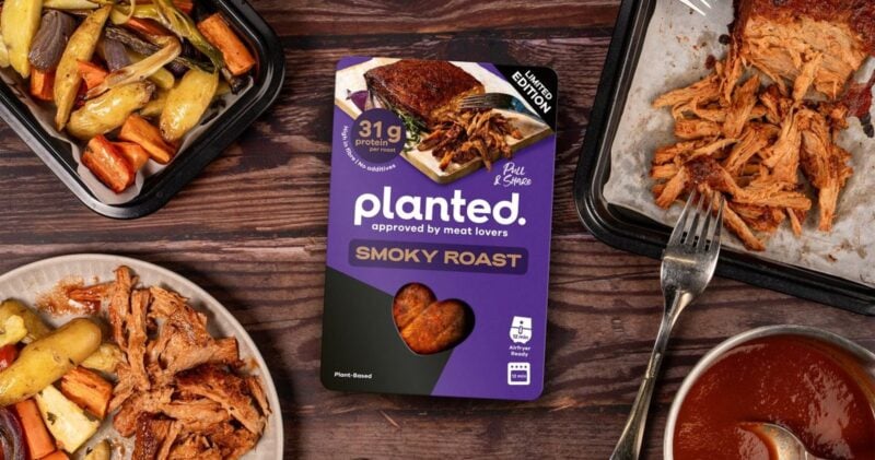Packung planted Smoky Roast Limited Edition auf einem Holztisch mit gezupftem Braten, Ofengemüse und Soße