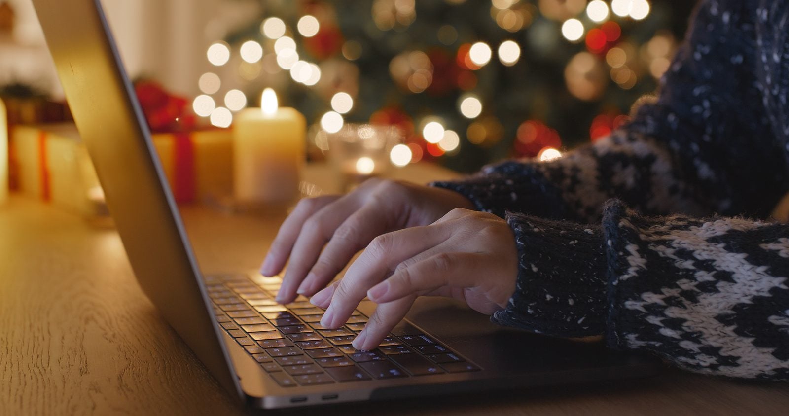 Hände tippen auf einem Laptop in weihnachtlicher Umgebung
