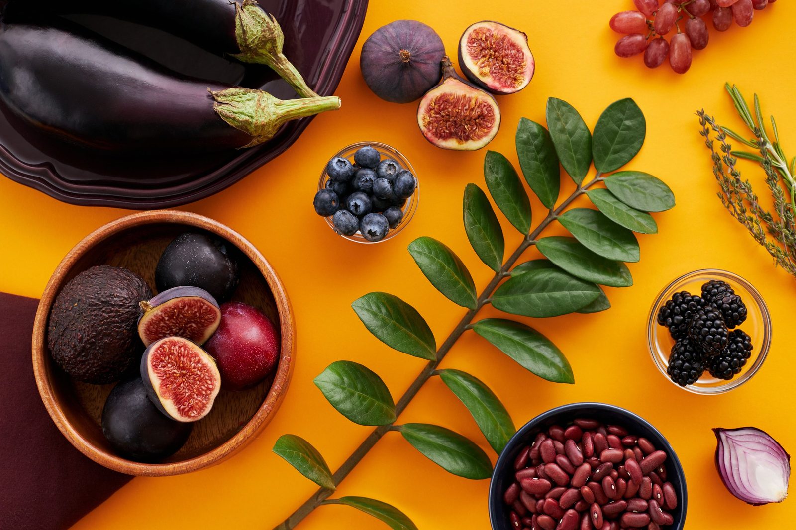 Feigen, Aubergine, Beeren, Trauben und Zwiebel auf farbigem Hintergrund