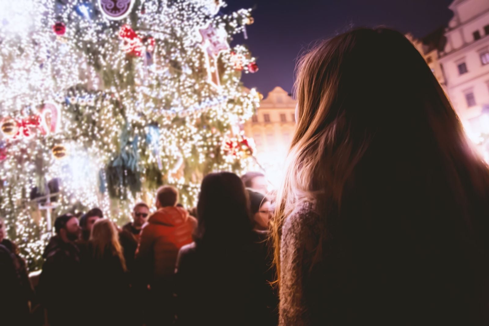 Symbolbild: Menschen vor einem hell erleuchteten Weihnachtsbaum am Abend