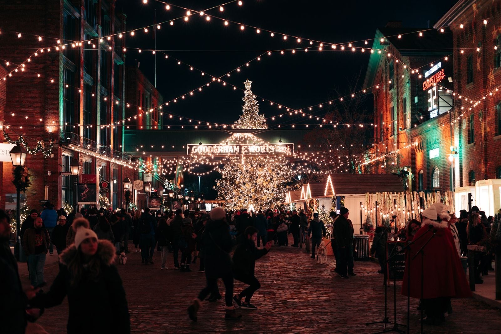 Symbolbild: Weihnachtsmarkt unter Lichterketten mit beleuchtetem Baum und vielen Menschen