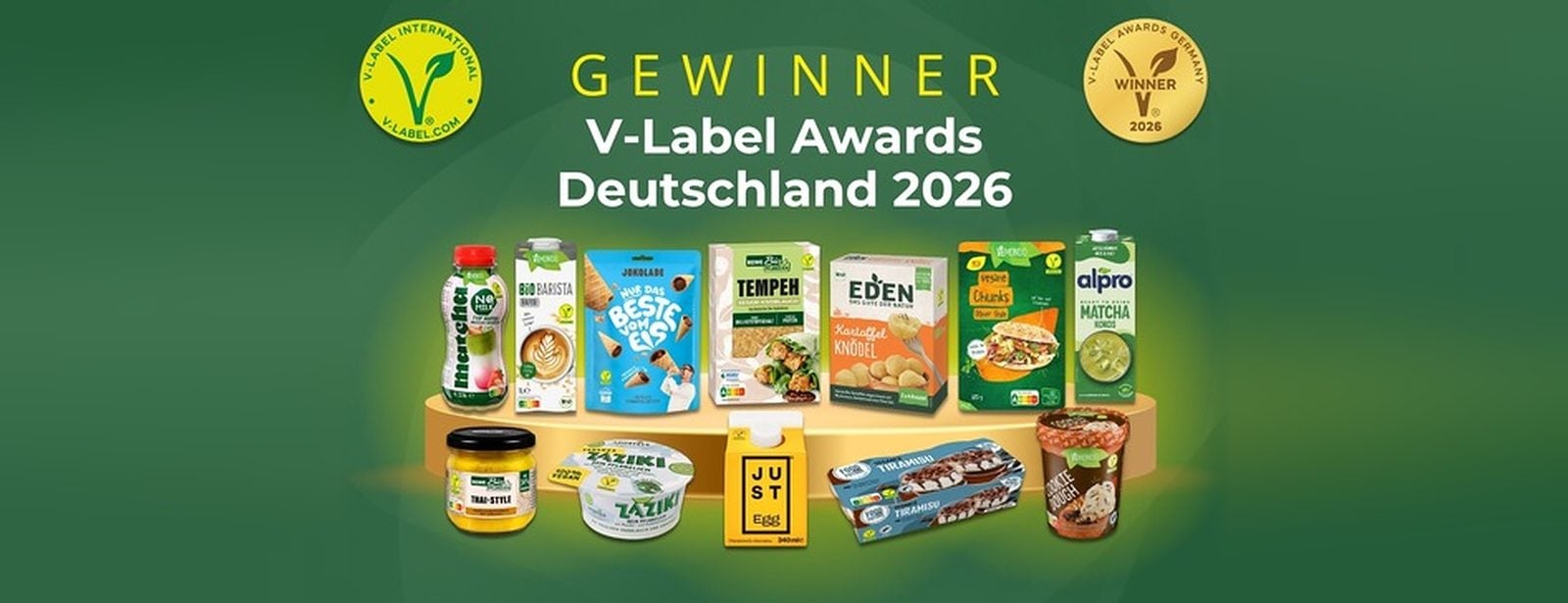 Die 14 Gewinnerprodukte der V-Label Awards Deutschland 2026 auf einem Podest, darüber der Schriftzug Gewinner