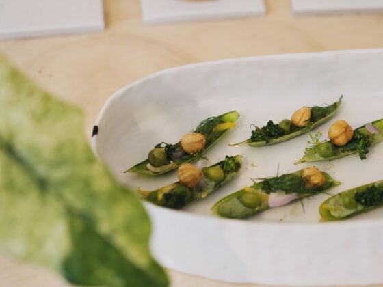 Angerichtete Zuckerschoten mit grüner Kräutercreme, Erbsen, Haselnüssen und Dill in einer weißen Keramikschale
